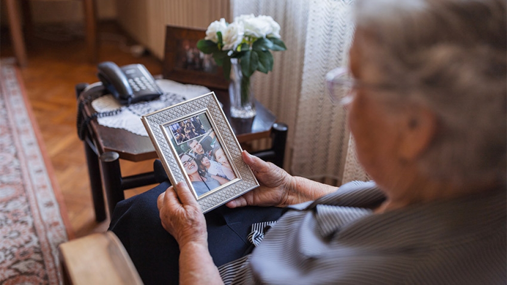 elderly woman family portrait frame looking at in hand