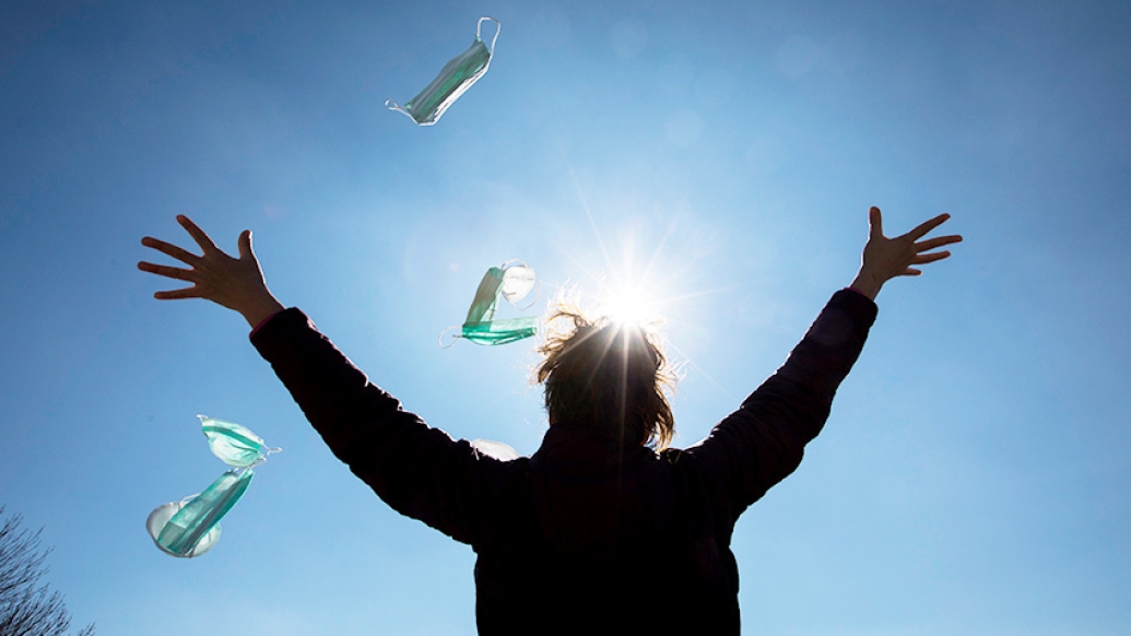 person throwing masks into the sky with sun