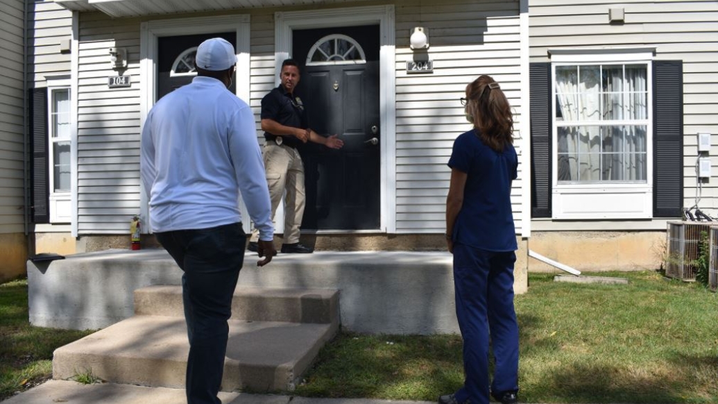 man at door and two people watching outside with masks on