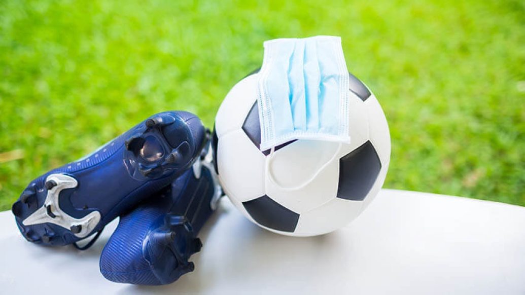 Soccer ball with cleats and mask near green field