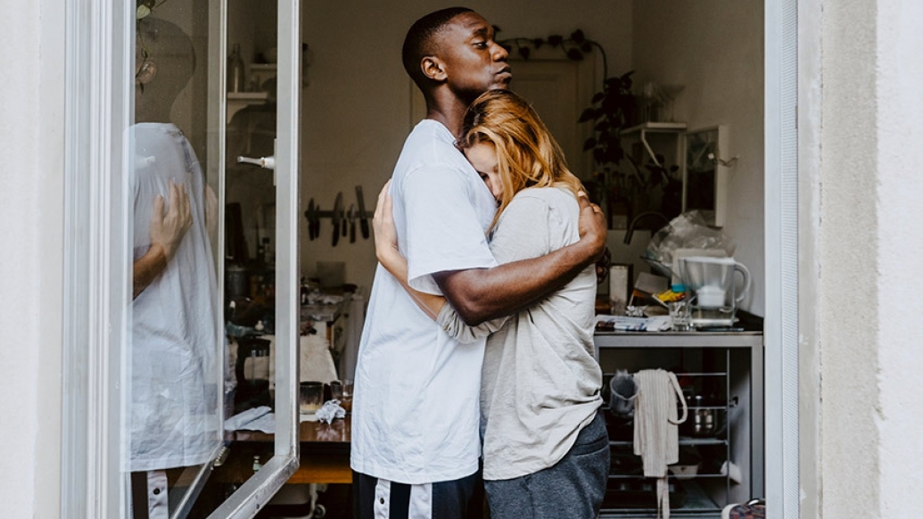 young man hugging woman in window