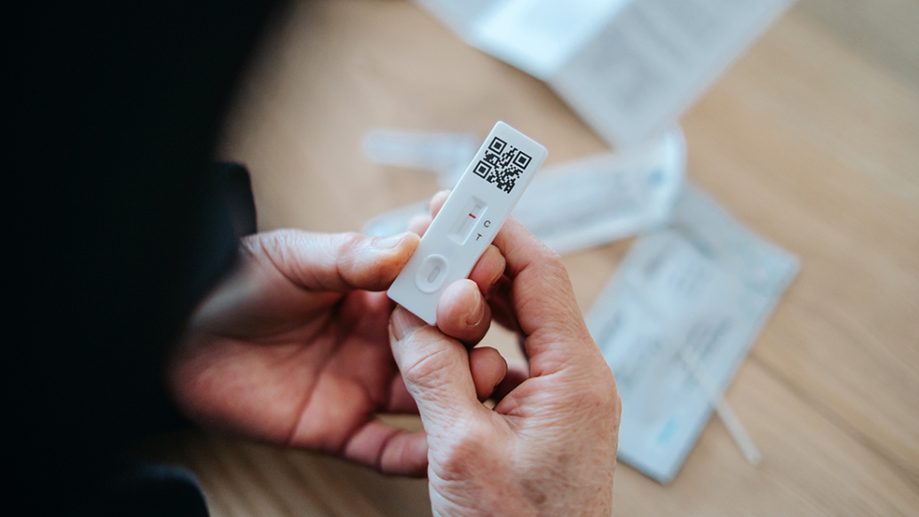 adult holding covid test low wrappings in background
