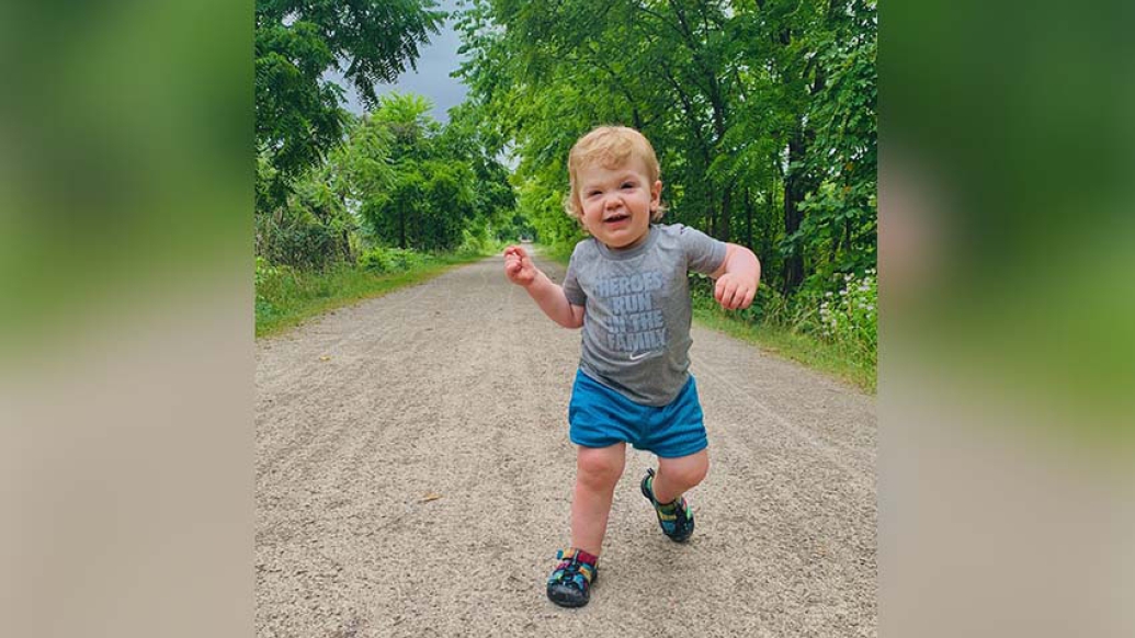 Toddler walking on dirt path surrounded by trees