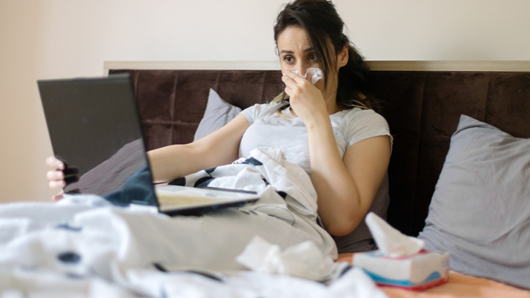 woman in bed blowing nose
