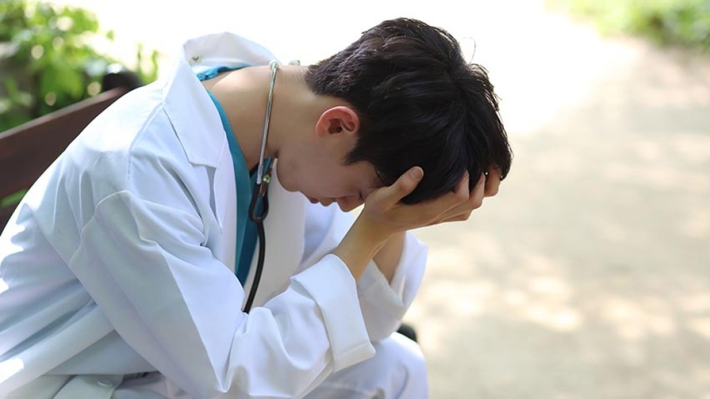 young doctor stressed on park bench