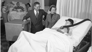 1950 photo of a polio patient in a hospital bed looking at a new TV set