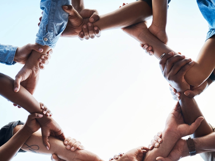 Unidentifiable people holding hands in a circle