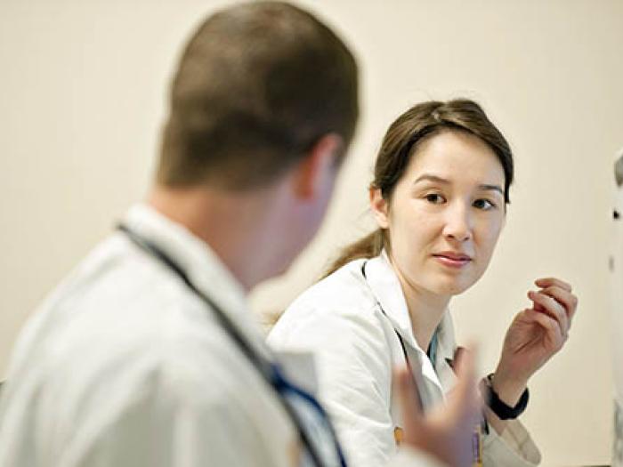 Female Asian physician in white coat wested with white male doctor with stethoscope