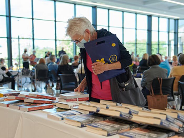 Elderly woman looking at books and magazines lying on table