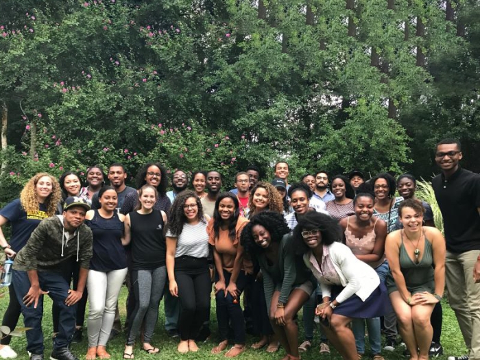 Group of diverse students standing in grass in front of trees