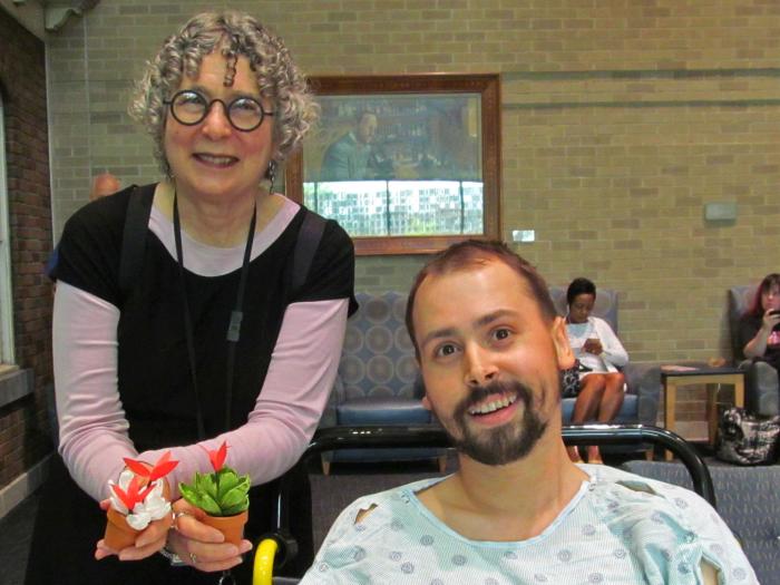 Woman standing holding two flowerpots next to smiling patient