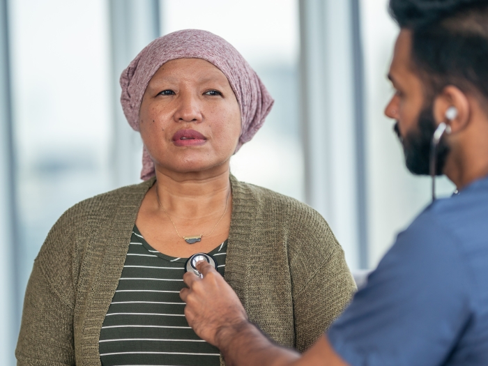 Woman with a headscarf having her heart checked by a man with a stethoscope.
