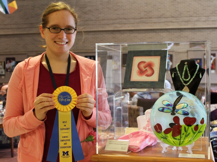 A Michigan Medicine employee holds up a ribbon earned for her art