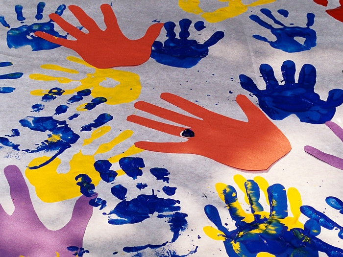 Colorful handprints in paint on a white sheet
