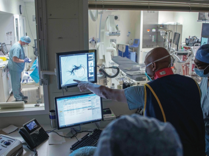 doctors in surgery case looking at screen blue scrubs