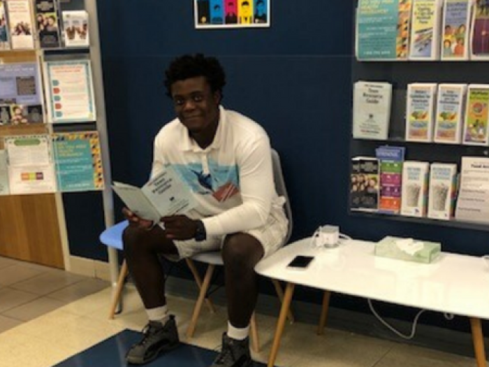 A young person sitting in the waiting room of a health center