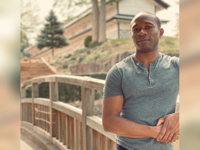 Man standing on a bridge wearing a gray t-shirt