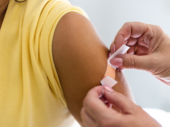 bandaid on arm after shot yellow shirt