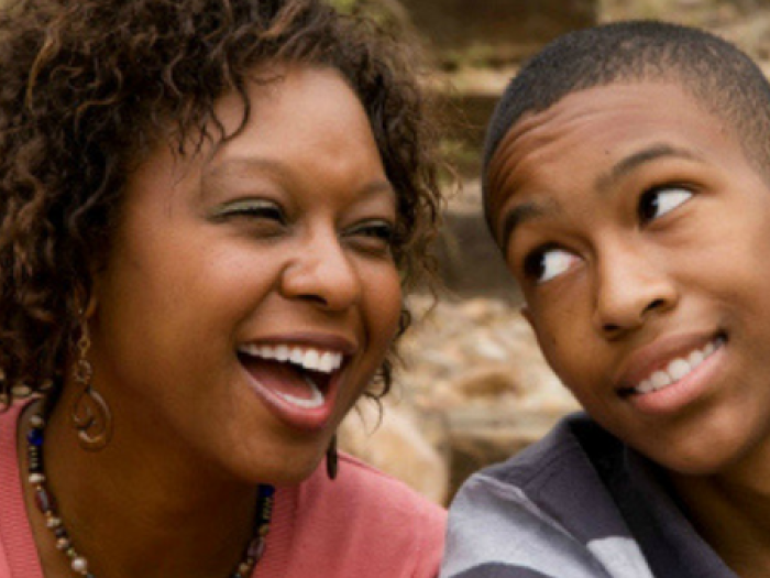 A girl is smiling while a boy looks at her candidly.