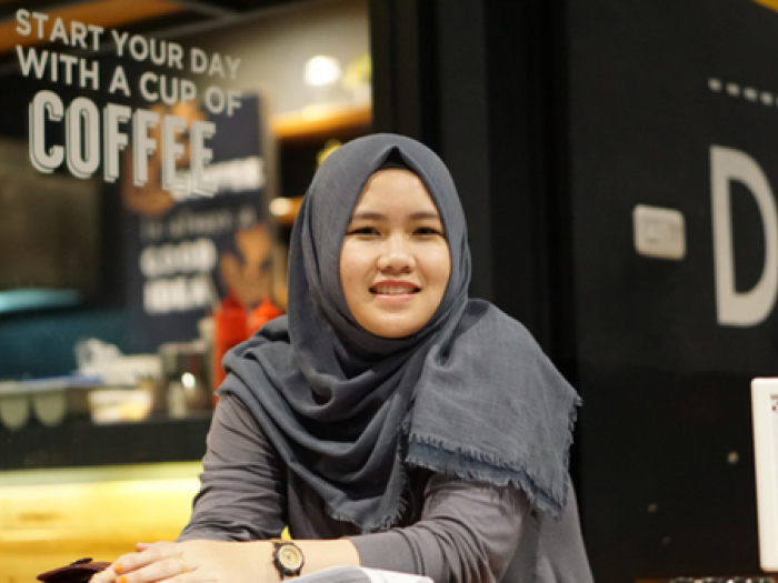 student in hijab smiles outside coffee shop
