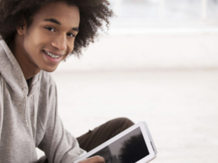 teen smiles while holding tablet