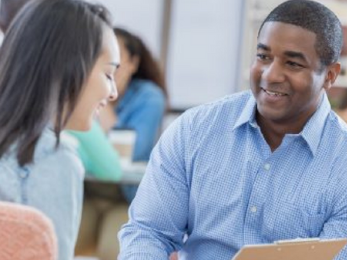 Male staffer smiles while talking with student