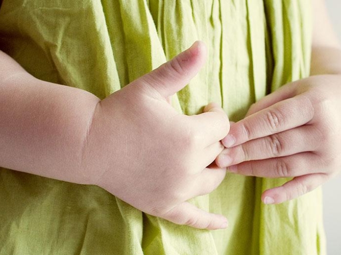 toddler in a green shirt with hands on their stomach