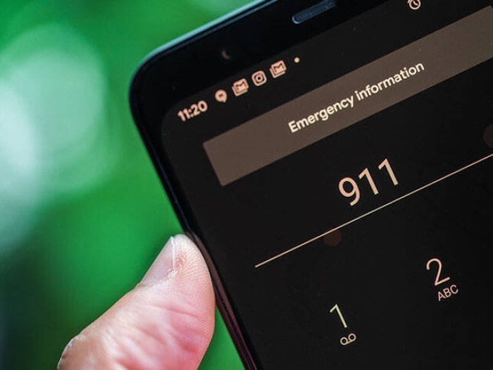 Hand holding cell phone calling 911