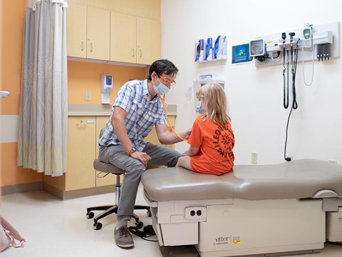doctor in patient room using stethoscope on patient 