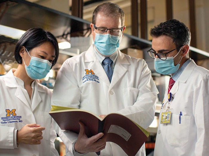 Doctors huddled with masks and labcoats on looking at book