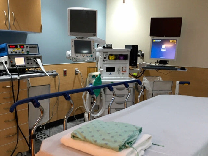 Empty hospital bed with monitors and machines in hospital room
