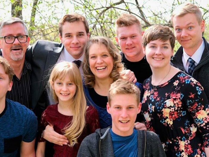 family gathered outside taking a photo in front of trees in nice clothing