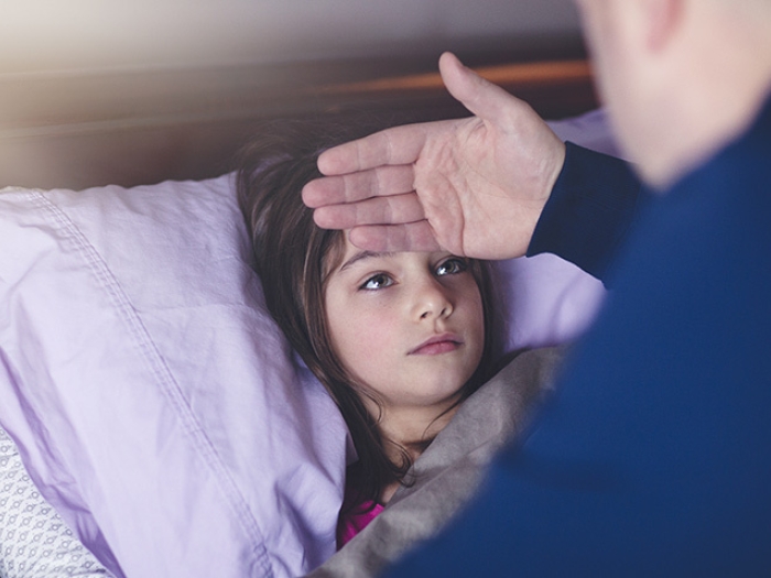father checking temperature on child in bed