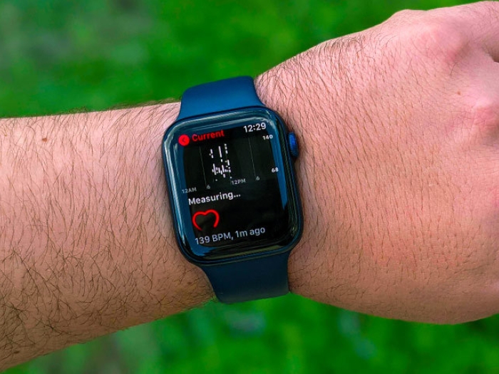 man's arm with eye watch over green field 