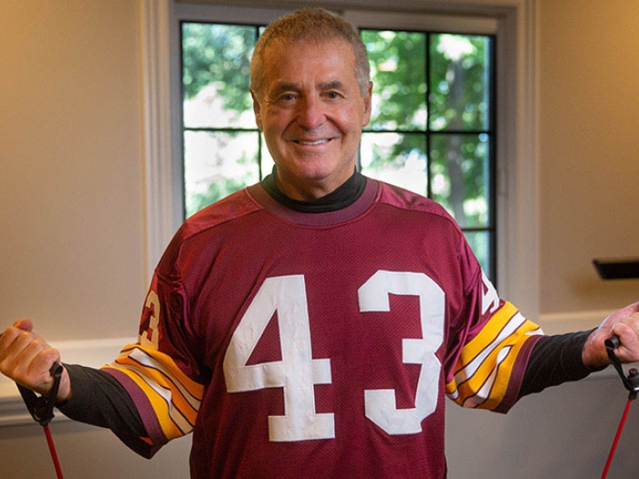 Man in red football jersey exercising with bands and smiling in room