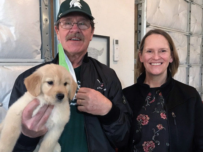 Man and woman couple holding puppy smiling