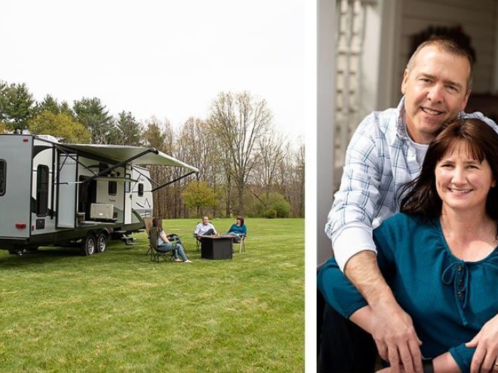 Man leaning over woman hugging and smiling near camper