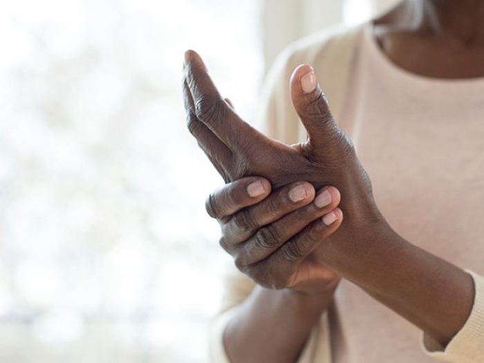 Woman in white shirt by window rubbing her hands
