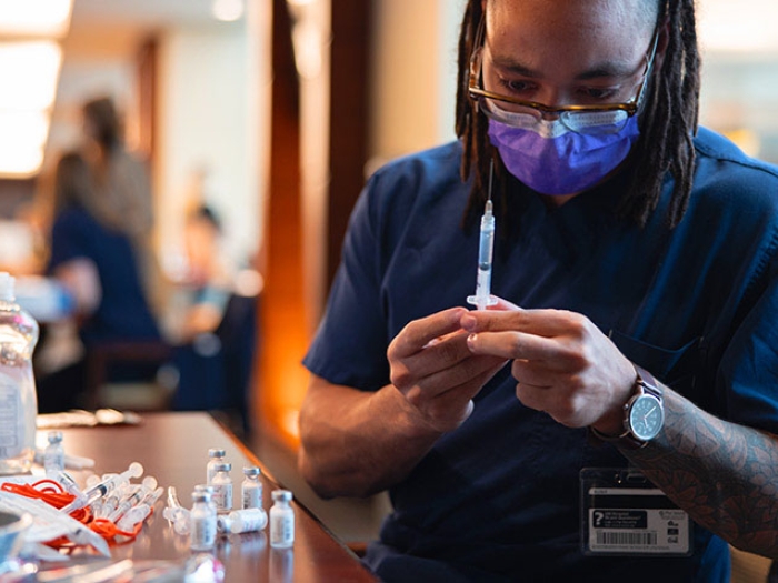 Nurse holding syringe vials with vaccine in clinic.
