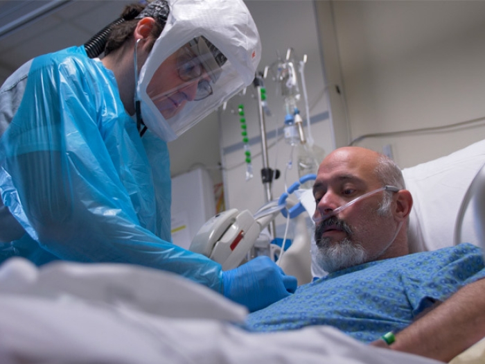 health care worker with patient in bed with COVID suiting on