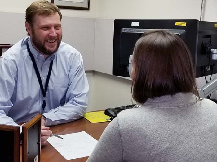 researcher in office talking with colleague at desk