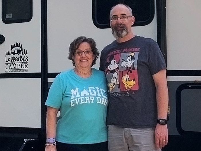 Couple standing by RV smiling