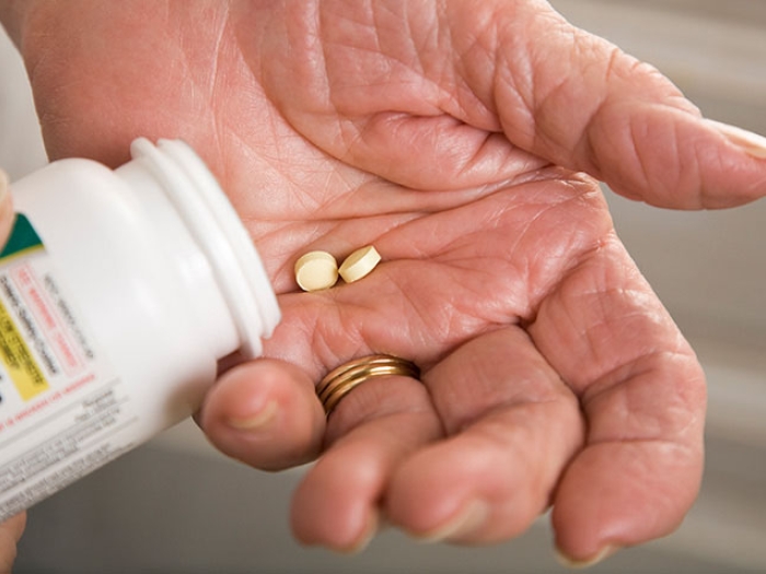 Hand pouring aspirin pills into hand