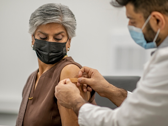 older woman bandage by doctor with mask on and she has a mask on
