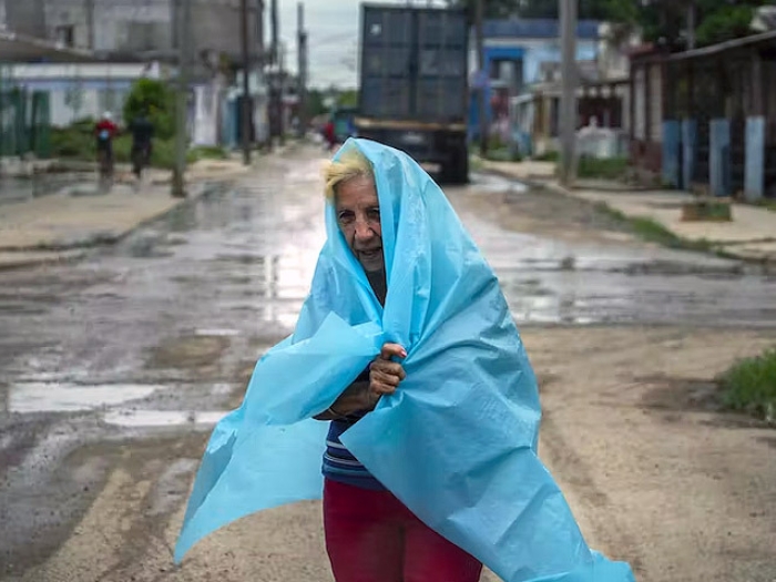 older woman with tarp over here in rain hurricane