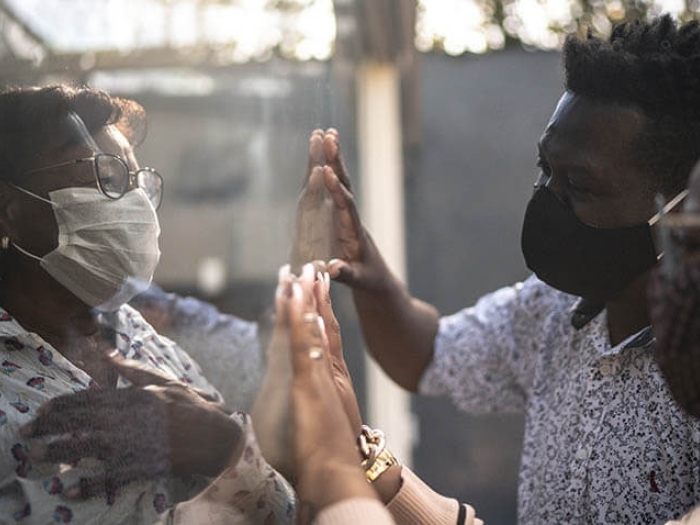 Visiting quarantined mother communicating through a glass window