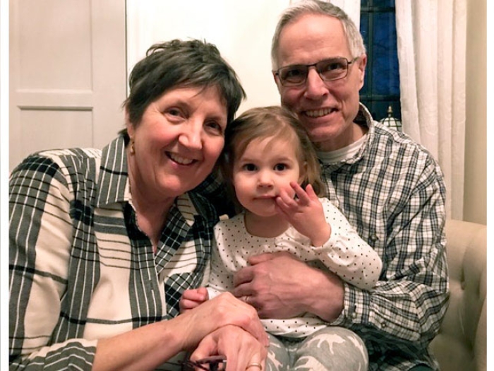 Woman and man wearing plaid smiling while holding child