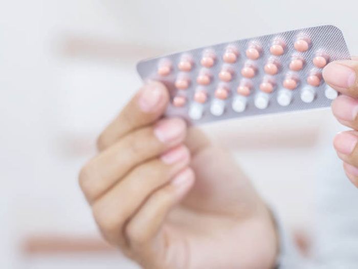 Woman hands opening birth control pills