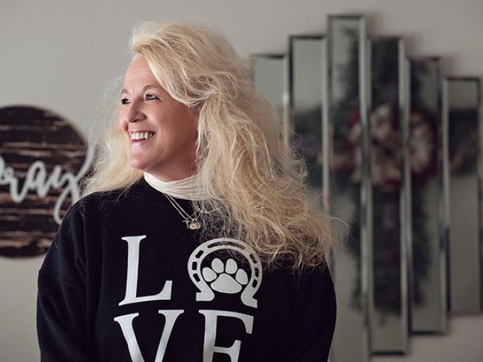 woman in black shirt with blonde hair staring off to side smiling