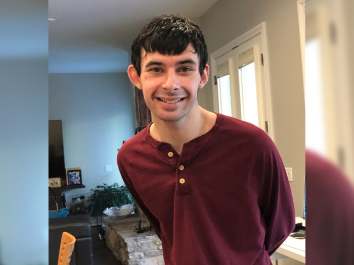 young man in red shirt smiling standing in kitchen